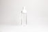 Tall glass container with white rubber wine bottle shaped top on an white backdrop.