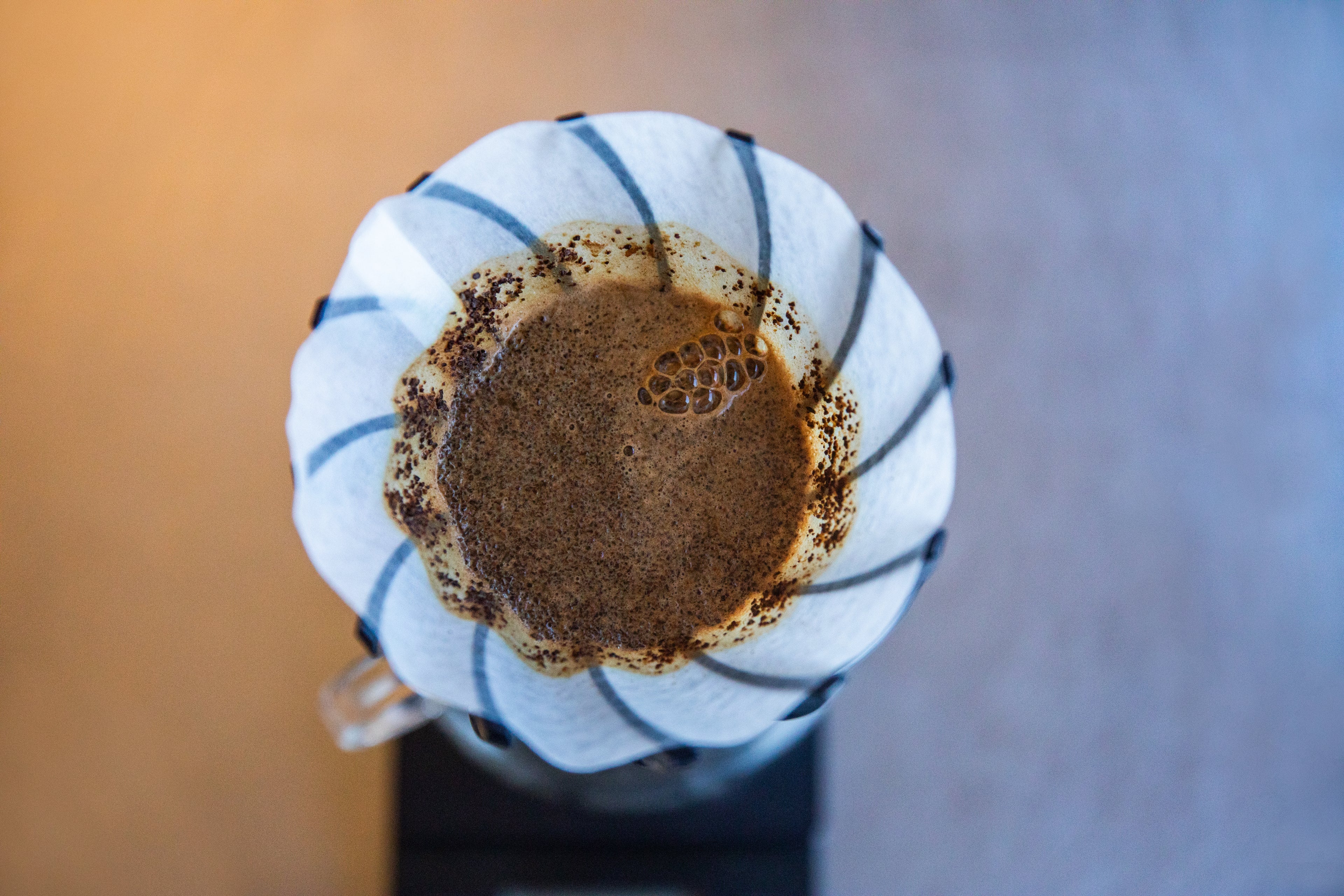 Pedal dripper, with a white filter and blooming coffee. On a white and yellow background