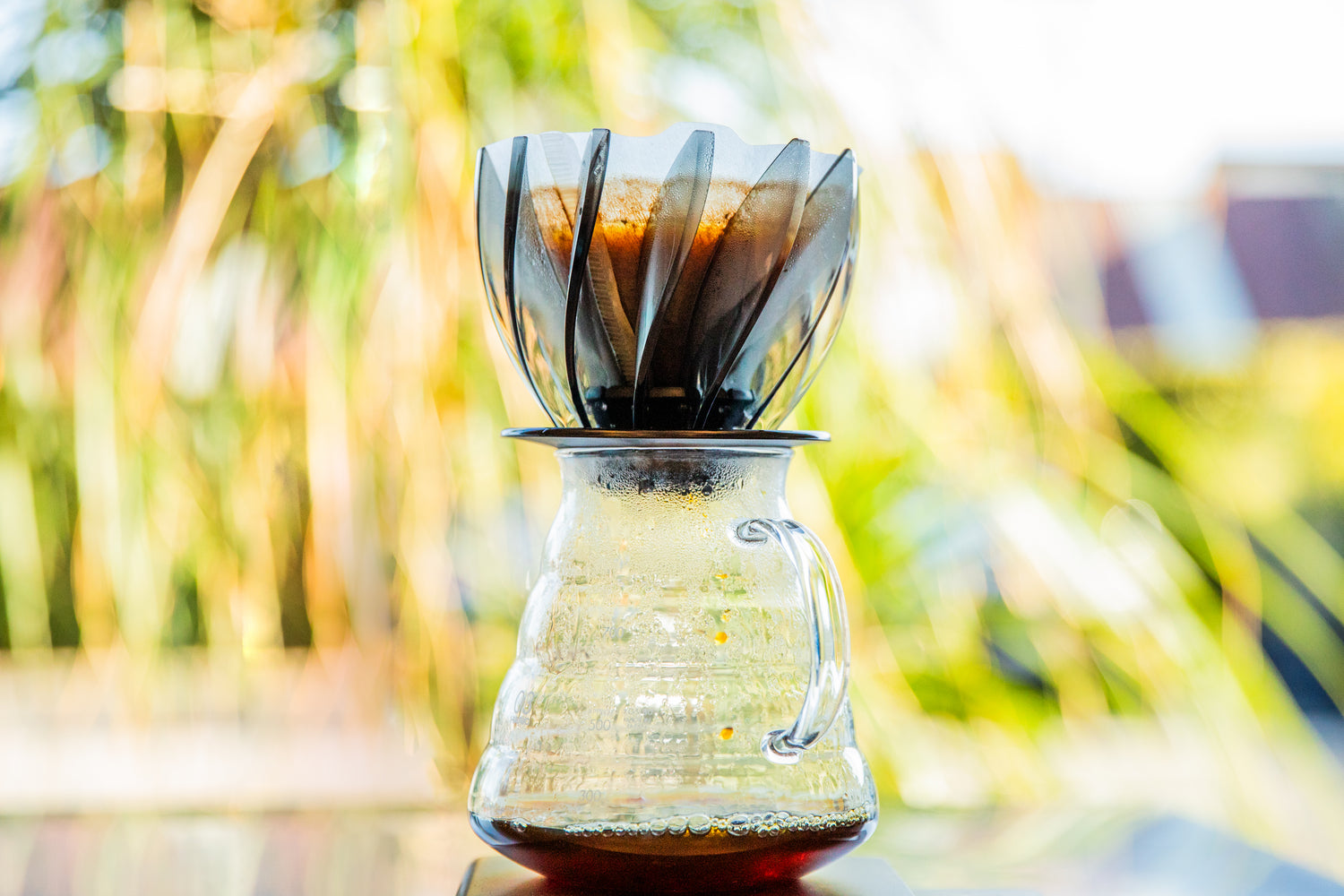 Transparent black pedal spiral dripper pour over coffee on top of a clear glass beehive shaped coffee sever.