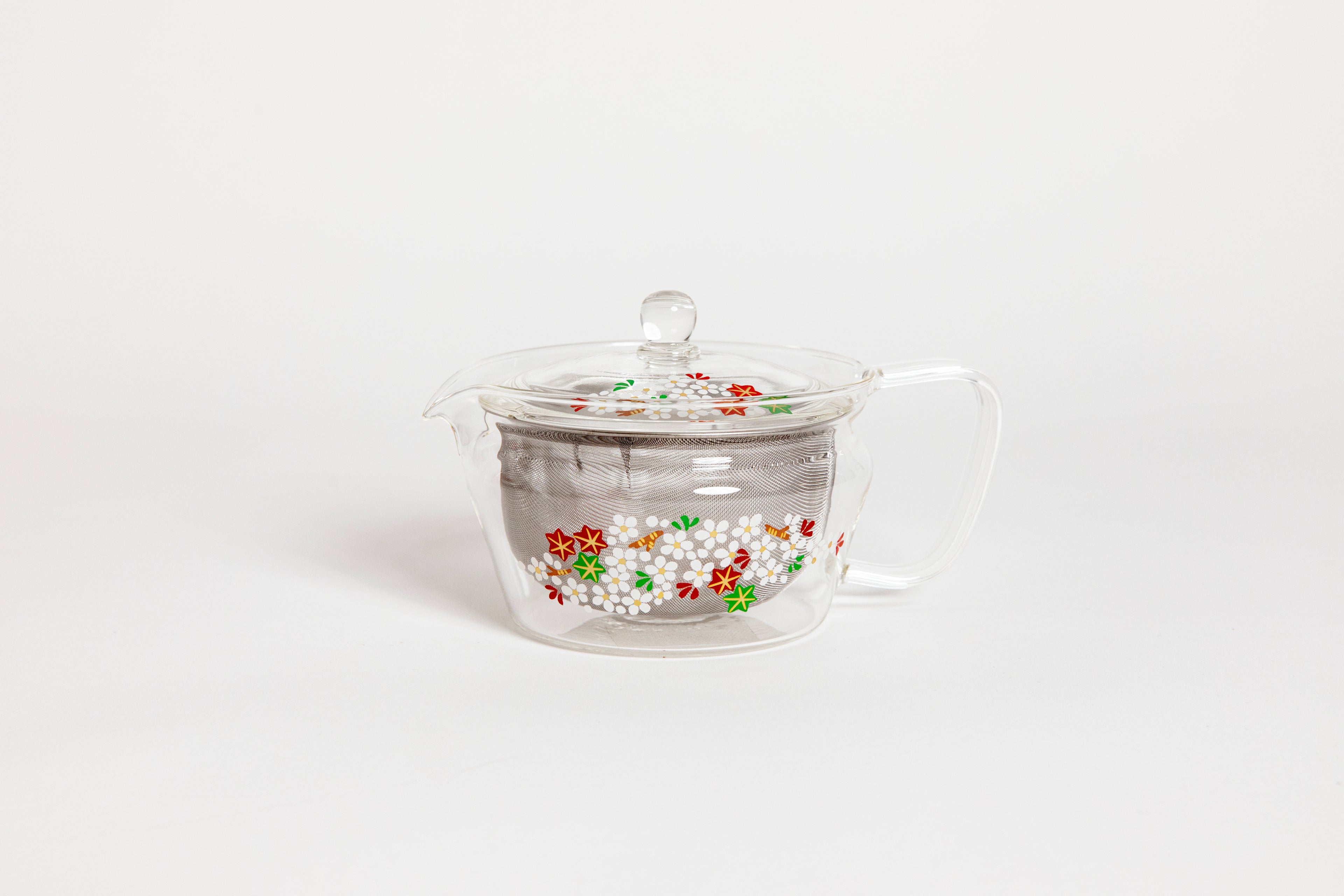 All glass tapered tea pot with flat bottom, all glass lid and handle, and metal mesh filter basket insert. Decorated with a yellow and white painting of &quot;Cloud Nishiki&quot;, a cloud-like cherry blossoms colored in  white, red, green and beautiful brocade-like autumn leaves. Set on white background